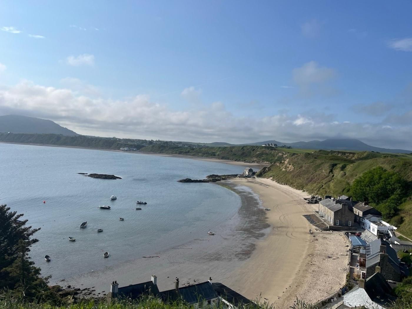 Une vue sur la côte, avec une plage de sable, des bateaux et des maisons le long du rivage.
