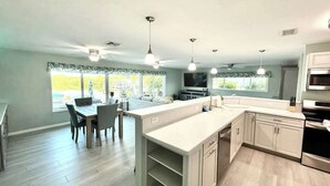 Una cocina moderna con comedor, ventanas amplias y horno empotrado.