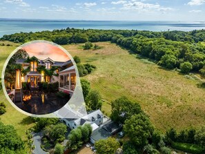 Ein großes Anwesen mit einem Haus, umgeben von üppiger grüner Natur und Blick auf das Meer.