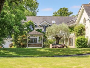 A residential property with a well-maintained lawn, a gazebo, and mature trees. - 5 Bed in East Cowes (oc-94807) (East Cowes)