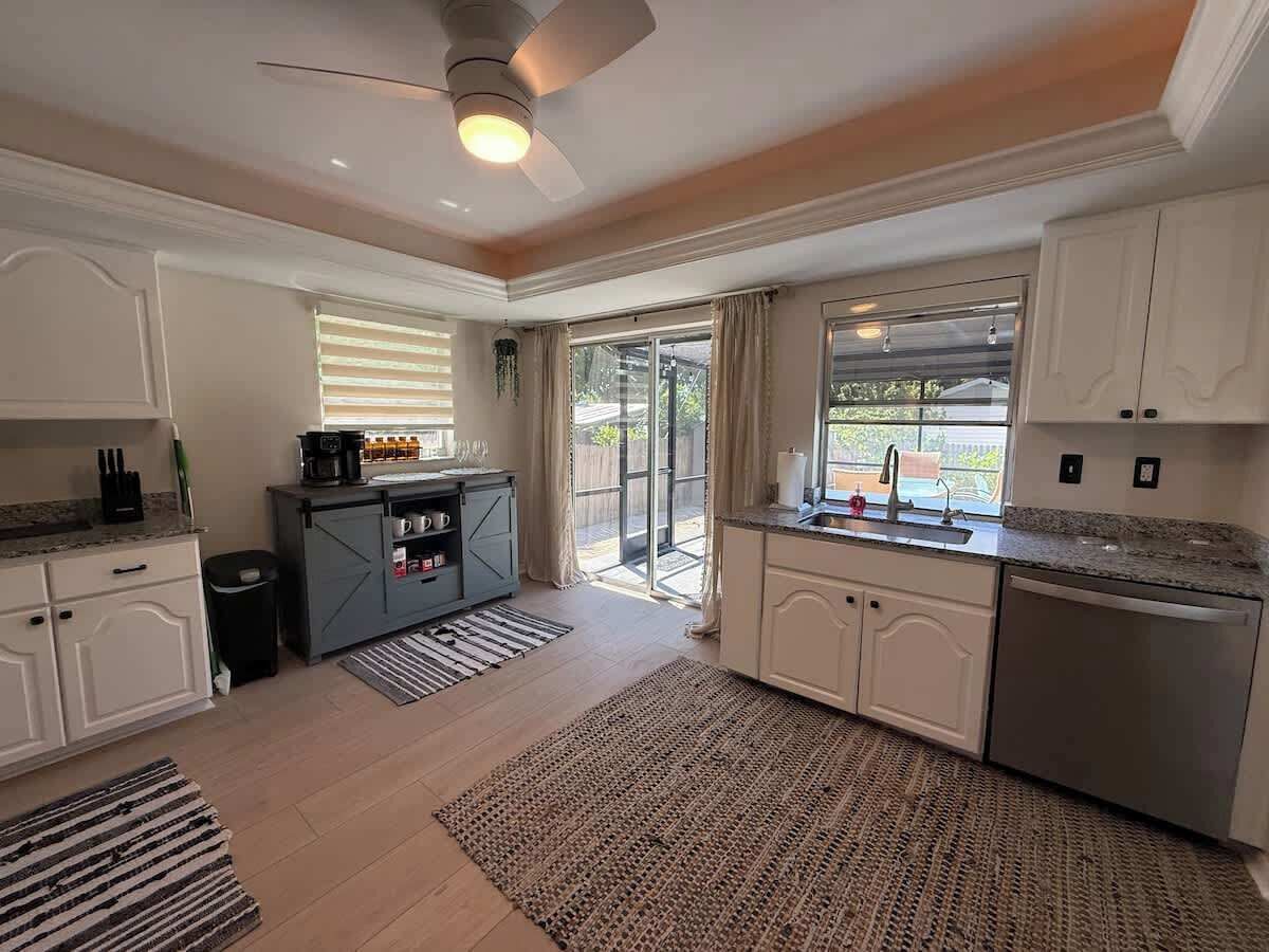 A modern kitchen with a central island, a dining area with a table, and a view of the outdoors.