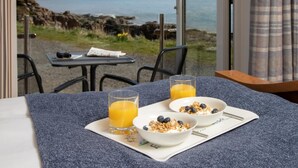 Ein Frühstückstisch mit Stühlen und Blick aufs Meer.