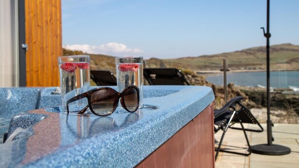 Eine Bar mit Gläsern Wasser und Sonnenbrillen, mit Blick auf eine Küstenlandschaft.