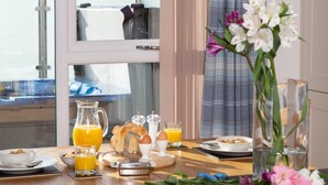 Une table de petit-déjeuner avec une machine à café, des œufs, du pain et du jus d’orange.