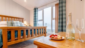 Een slaapkamer met een houten bed, een nachtkastje met een fles en glazen, en een bord met aardbeien.