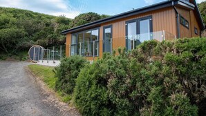 A modern house with large windows, a wooden exterior, and a surrounding landscape. - 1 Bed in Castle Douglas (oc-rasc2) (Auchencairn)