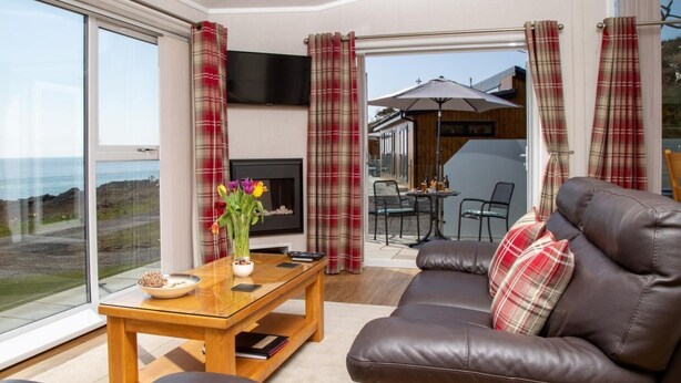 A modern living room with a leather sofa, a wooden coffee table, and a TV. - 1 Bed in Castle Douglas (oc-rasc4) (Auchencairn)