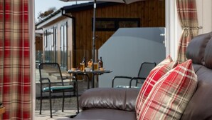 A cozy outdoor seating area with a table, chairs, and a large umbrella. - 1 Bed in Castle Douglas (oc-rasc4) (Auchencairn)