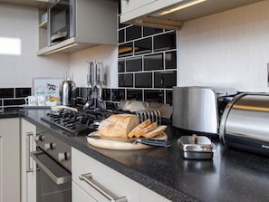 Eine moderne Küche mit einem Gasherd, einem Toaster und einem Schneidebrett mit Brot.