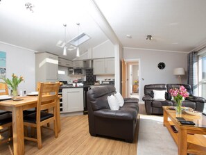 Eine moderne Wohnung mit Essbereich, Wohnzimmer mit Sofa, Küche und Blick ins Freie.