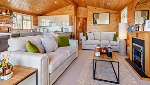 Een gezellig interieur van een chalet, met een zithoek, keuken en een open haard.
