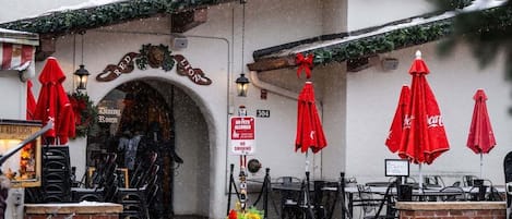 Un restaurant avec une terrasse, un panneau indiquant qu’il est interdit d’y entrer avec des animaux de compagnie, et une couronne de Noël.