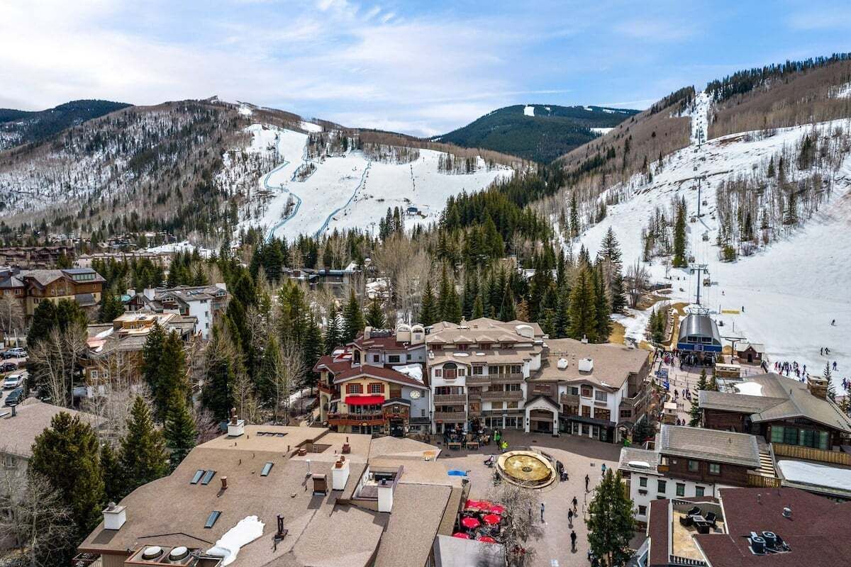 Een skigebied met gebouwen, een gondellift en een berg op de achtergrond.