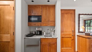 A compact kitchen with wooden cabinets, a microwave, a refrigerator, and a window with a view. - Studio - Ski In/Ski Out Vail Village 204 (Vail)