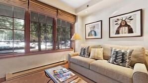 A living room with a sofa, a coffee table with magazines, a lamp, and two framed pictures on the wall. - Studio - Ski In/Ski Out Vail Village 204 (Vail)