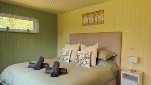 A bedroom with a bed, pillows, a nightstand, and a window. - 1 Bed in Conwy (oc-95098) (Ty'n-y-groes)