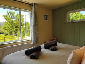 A bedroom with a bed, a window with curtains, a radiator, and a picture on the wall. - 1 Bed in Conwy (oc-95098) (Ty'n-y-groes)