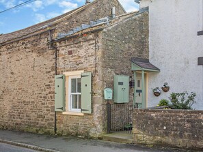 A stone building with a window and a door, a small gate, and a wall-mounted mailbox. - 1 Bed in Leyburn (oc-95072) (West Witton)