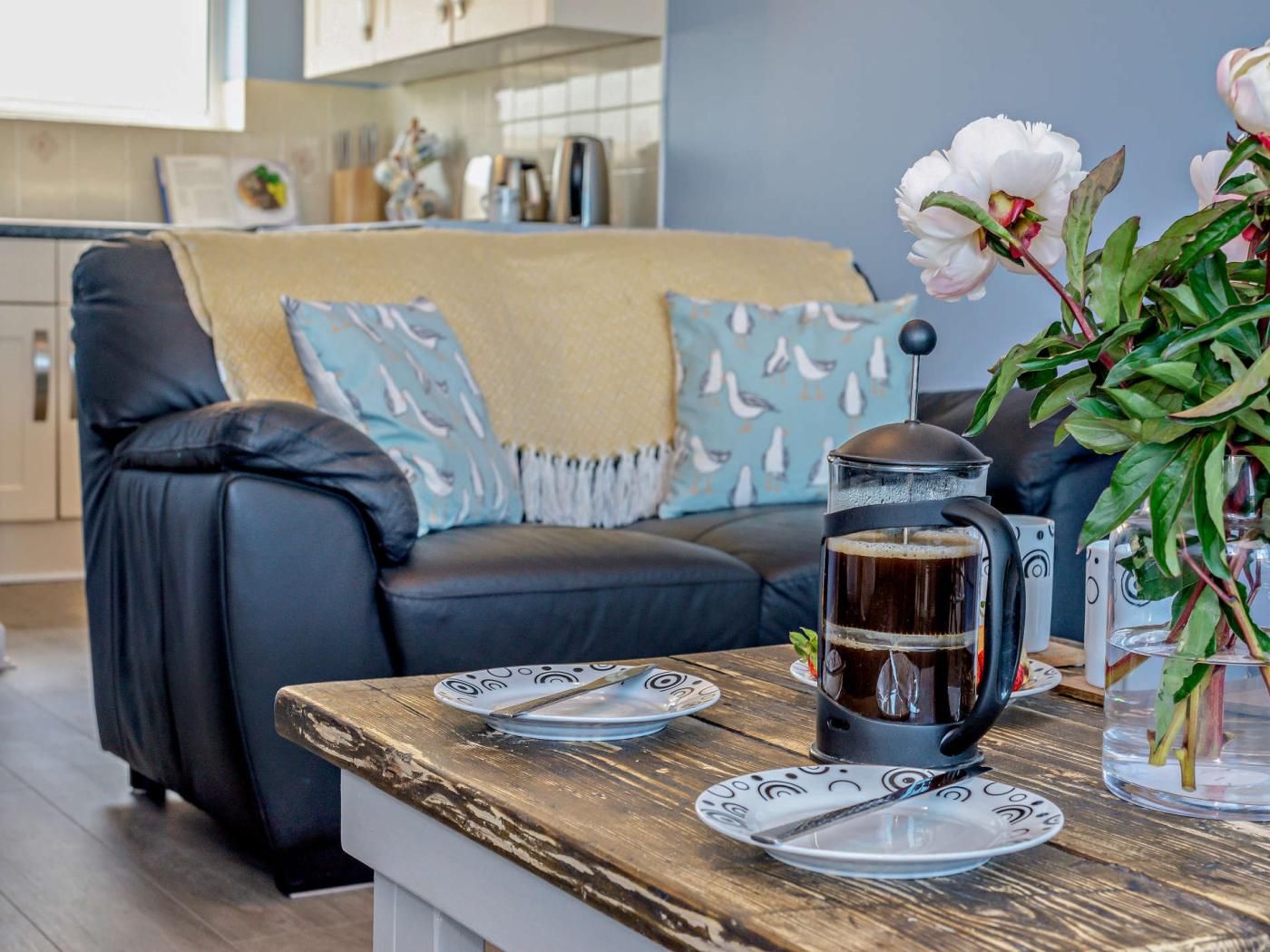 A cozy living room with a coffee table, a sofa, and a decorative plant.