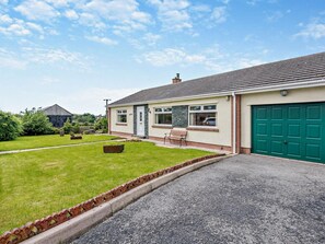 Une maison d’habitation avec un jardin devant, une allée et un garage.
