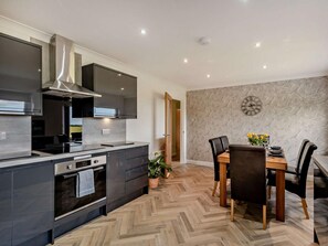 A modern kitchen with a central island, built-in oven, and stainless steel appliances. - 3 Bed in Cockermouth (oc-95115) (Eaglesfield)