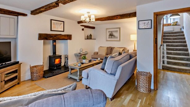 Una sala de estar acogedora con chimenea, un sofá, un televisor y una escalera.