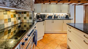 Una cocina con salpicadero de azulejos, vigas de madera y estufa.