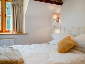 A bedroom with a bed, a window with curtains, a wall-mounted light, and a radiator. - 2 Bed in Chepstow (oc-95046) (Chepstow)