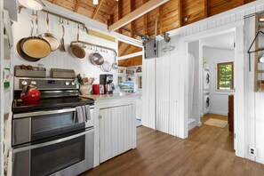 A kitchen with white cabinetry, a stove, and hanging pots.