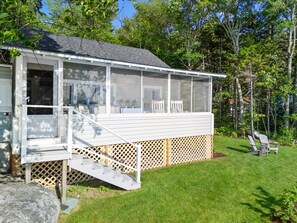A house with a covered porch, a staircase leading to the entrance, and a lawn area. - Sunset Cottage: Bayfront 3BR cottage with beach access, fire pit, WiFi, and Acadia nearby (Trenton)