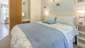 Une chambre à coucher avec un lit, des tables de chevet, une armoire et un miroir.