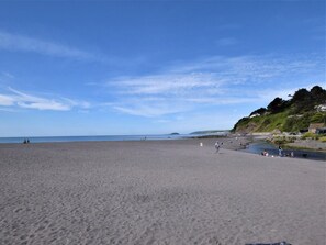 Ein Strand mit blauem Himmel, sandigem Ufer und einigen Personen.