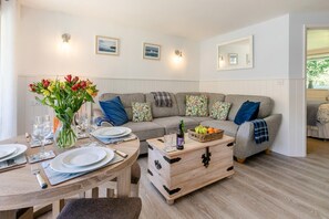 Ein gemütliches Wohnzimmer mit einer Couch, einem Holztisch und einem Esstisch für zwei Personen.