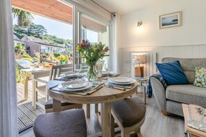 Uma área de refeições com uma mesa redonda para quatro pessoas, um sofá e vista para o exterior.
