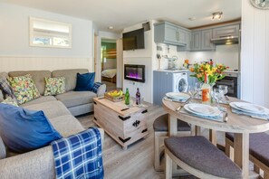 Ein modernes Wohnzimmer mit Sofa, Couchtisch und Essbereich mit Tisch für zwei Personen.