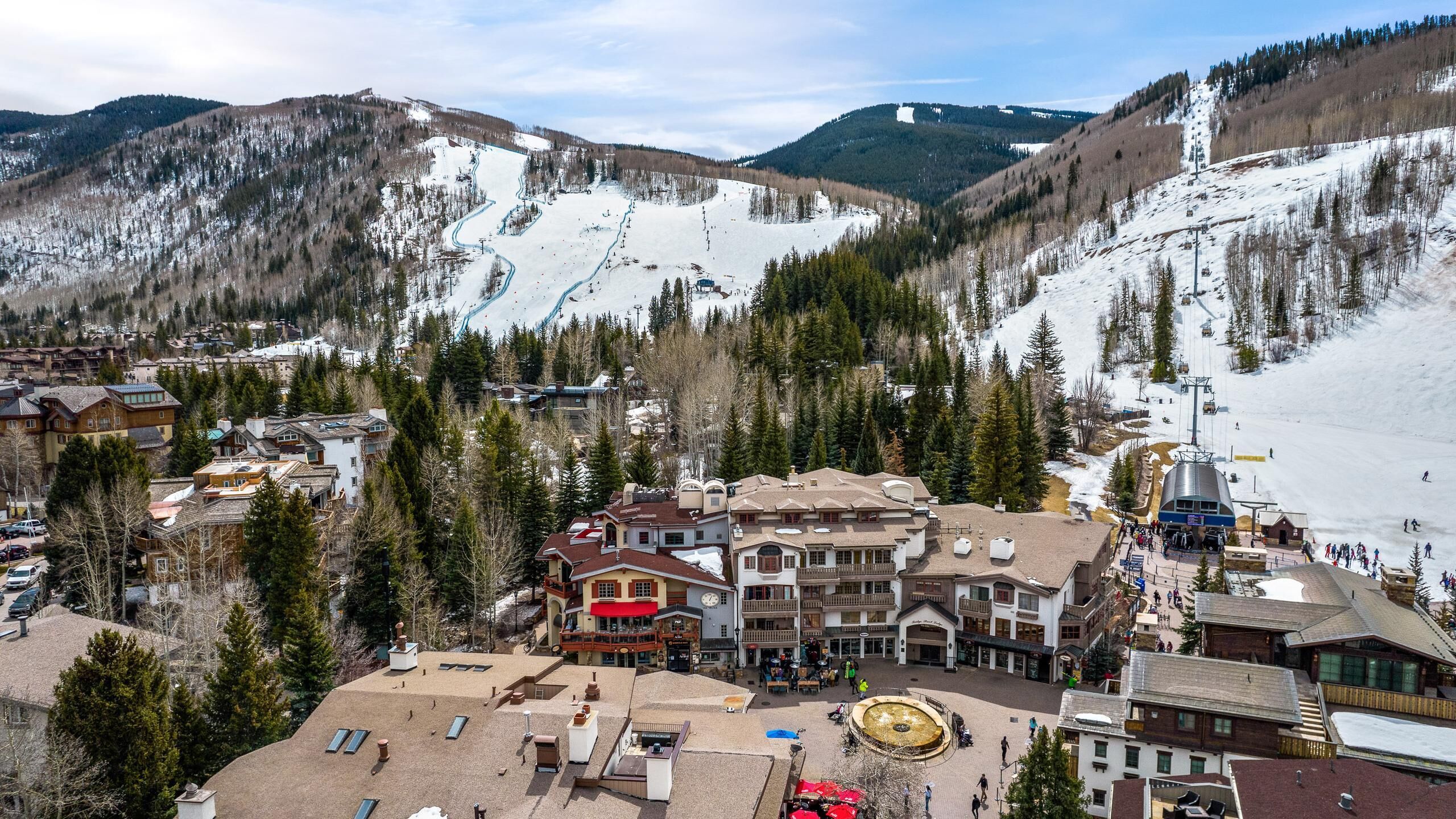 Une station de ski avec un bâtiment principal entouré de collines et d’arbres couverts de neige.