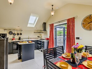 A modern kitchen with a central island, a dining area with yellow plates, and a clock on the wall. - 2 Bed in Stoke-on-trent (oc-94790) (Waterhouses)