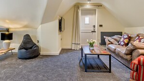 A cozy loft bedroom with a sloped ceiling, a bed, a seating area with a bean bag, a coffee table, and a radiator. - 2 Bed in Stoke-on-trent (oc-94790) (Waterhouses)