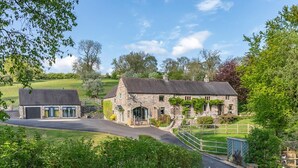 A stone building with a driveway leading to a gated entrance, surrounded by greenery. - 2 Bed in Stoke-on-trent (oc-94790) (Waterhouses)