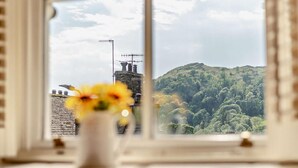 Una ventana con vistas a una colina verde y un edificio con antenas.