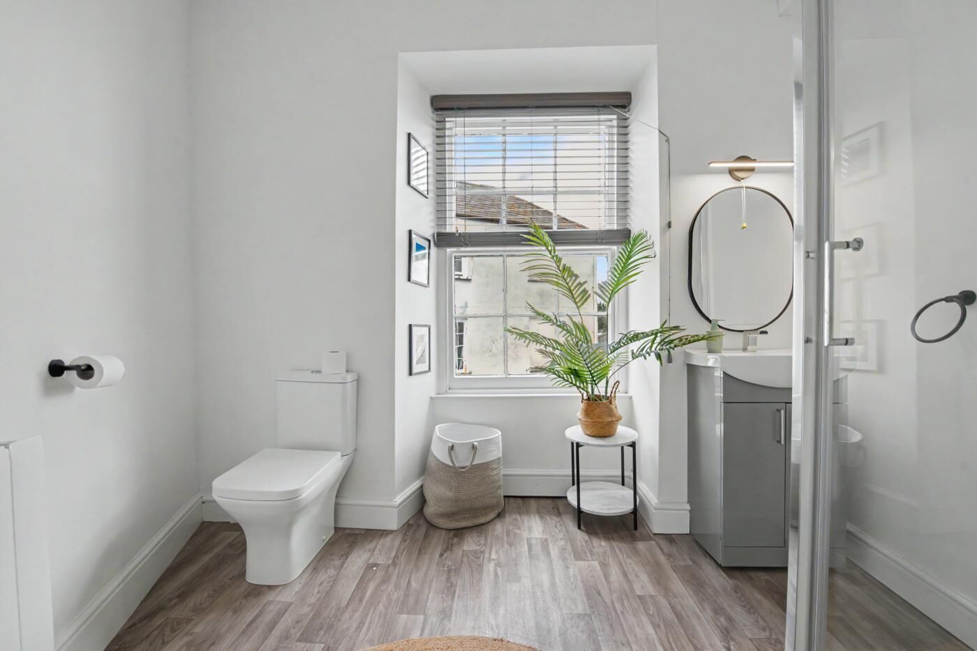 Ein modernes Badezimmer mit Toilette, Bidet, Waschbecken und einem Fenster mit Jalousien.