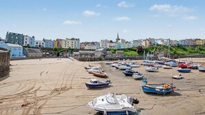 Eine Küstenstadt mit bunten Häusern, einem Sandstrand und zahlreichen vor Anker liegenden Booten.