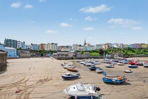 Eine Küstenstadt mit bunten Häusern, einem Sandstrand und zahlreichen vor Anker liegenden Booten.