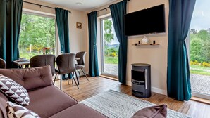Ein modernes Wohnzimmer mit einer Couch, Sesseln, einem Fernseher und einem Kamin.