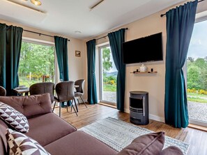 A modern living room with a sofa, chairs, a TV, and a fireplace. - 2 Bed in Beauly (oc-95056) (Kiltarlity)