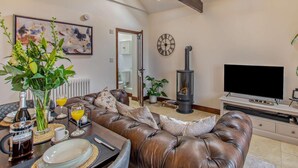 Ein Wohnzimmer mit Ledersofa, Fernseher, Kamin, einer Uhr und einem Bild an der Wand.