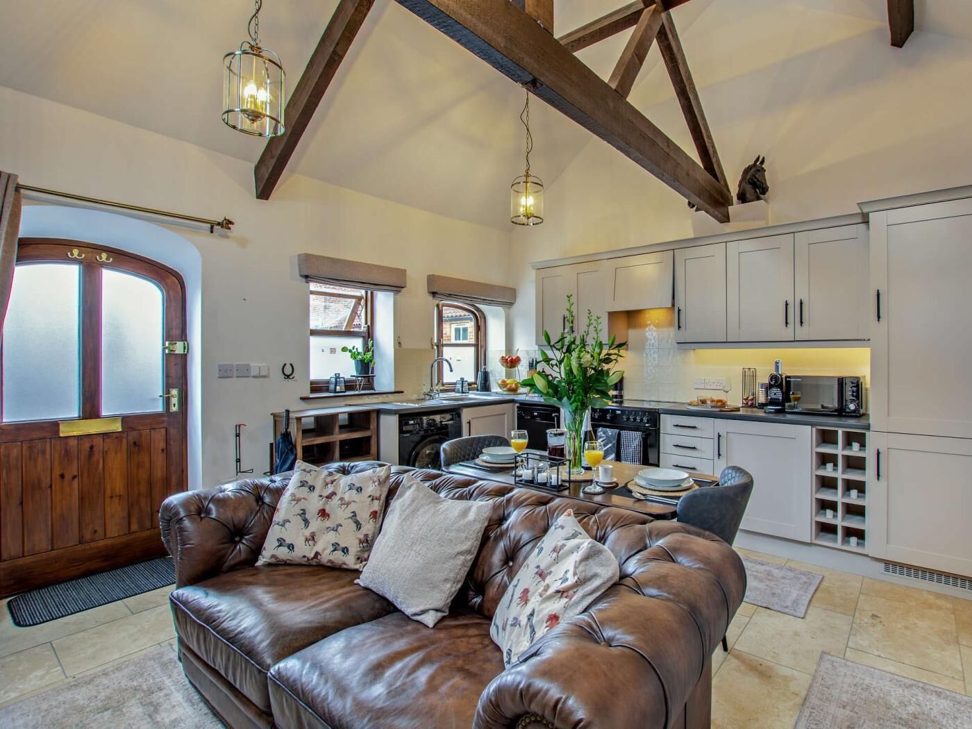 A cozy living room with a leather sofa, a dining area with a table and chairs, and a kitchen with modern appliances.