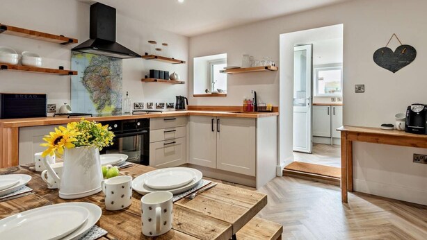 A modern kitchen with wooden countertops, a map on the wall, and a dining area with a wooden table set for four. - 2 Bed in Frizington (oc-95126) (Arlecdon)