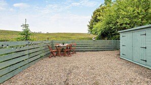 A patio area with a table and chairs, surrounded by a wooden fence and a shed. - 2 Bed in Frizington (oc-95126) (Arlecdon)