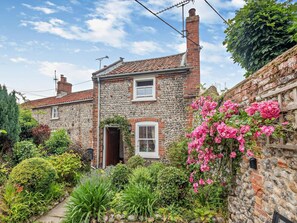 A stone house with a garden, a wooden fence, and a clear sky. - 1 Bed in Cromer (oc-60268) (Northrepps)